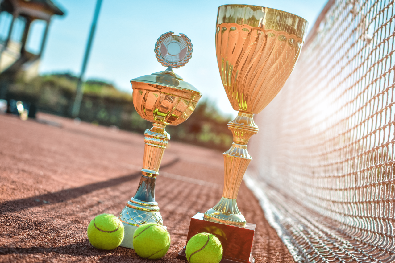 zwei Pokale mit Tennisball auf Tennisplatz Tennisnetz